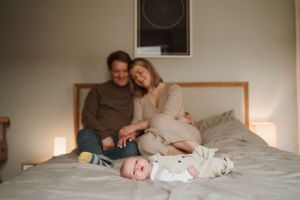 Family lounging together on white bedding during lifestyle photoshoot.