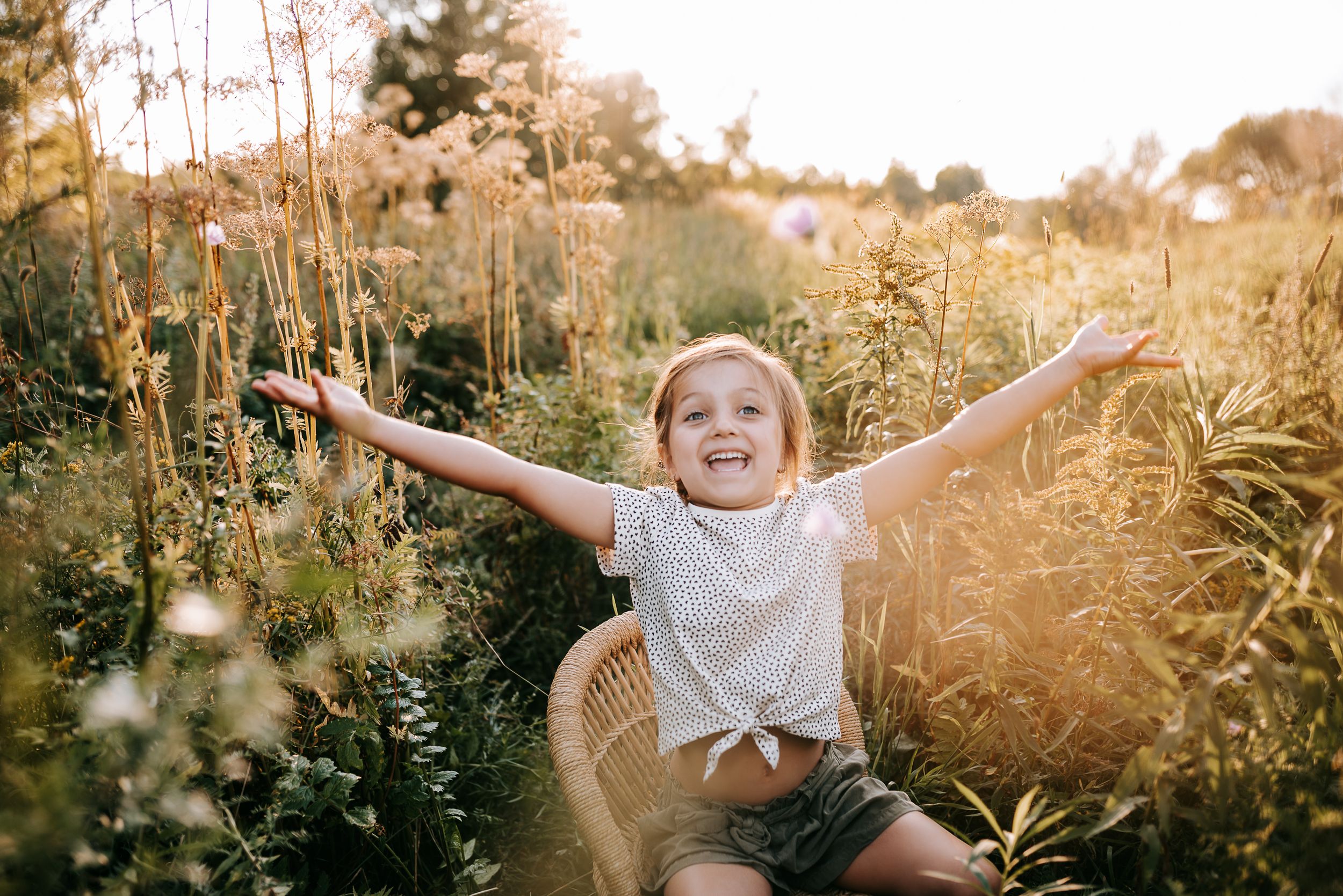 Joyful child with arms spread wide in field of golden wildflowers.