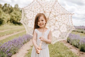 Young one holding a delicate lace parasol in a lavender field.