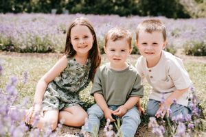Three young ones sitting together in a blooming lavender field.