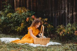 Yellow dress and picnic basket create a charming outdoor scene against dark wooden backdrop.