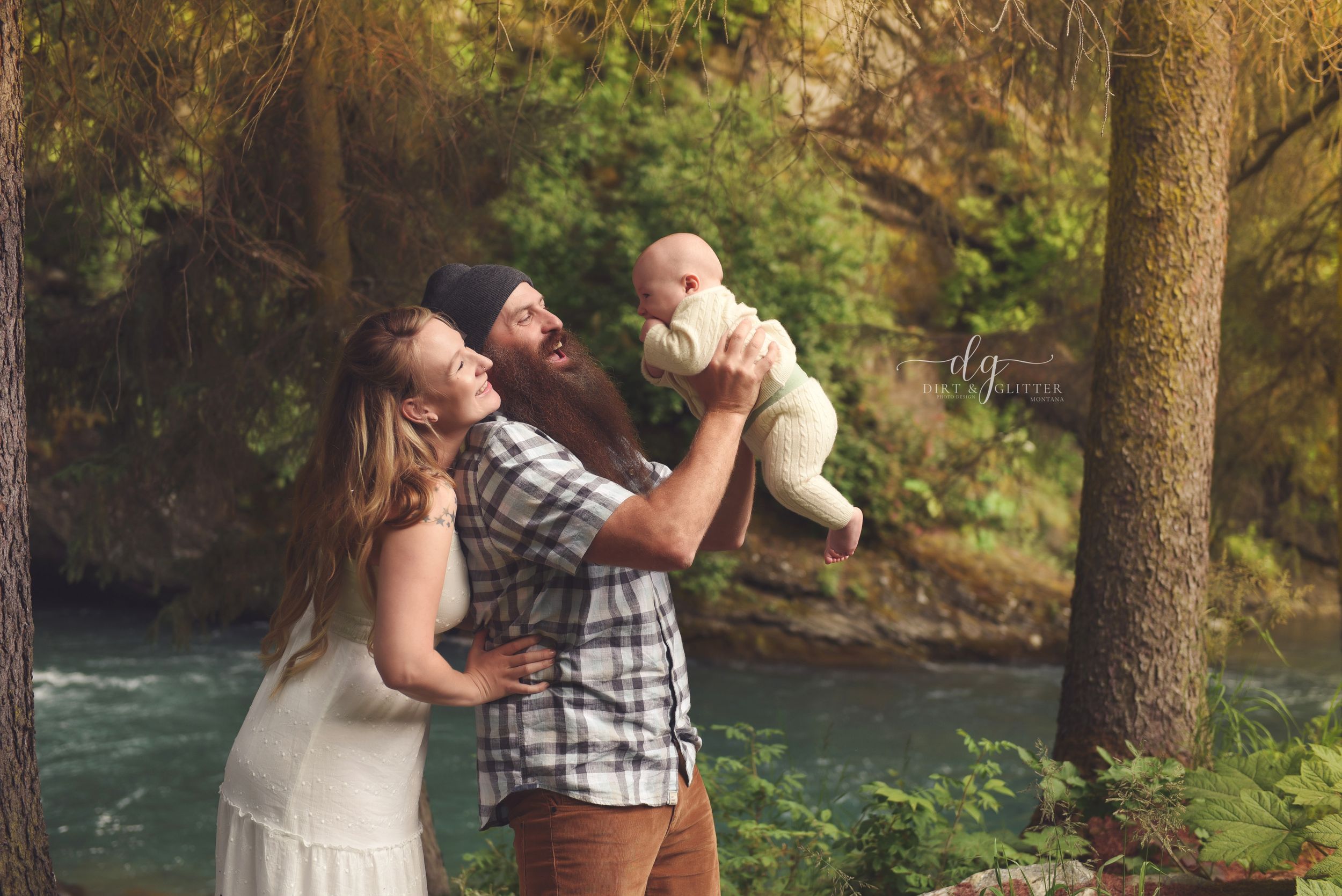 mom and dad holding baby in the alaska woods