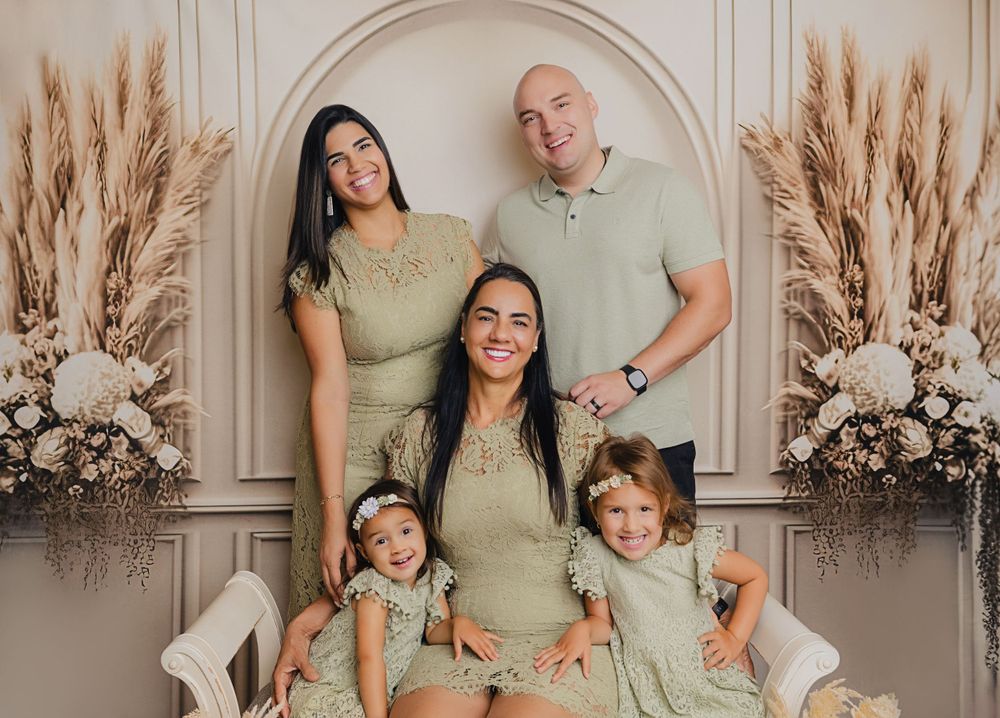 Candid family portrait with everyone wearing matching sage green outfits against neutral backdrop.