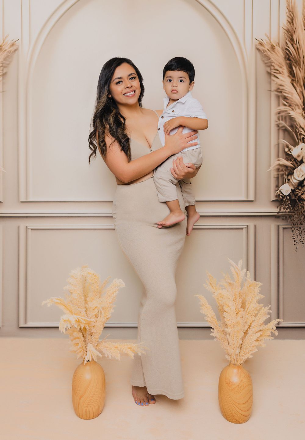 Beautiful studio portrait with arched backdrop and decorative pampas grass in golden vases.