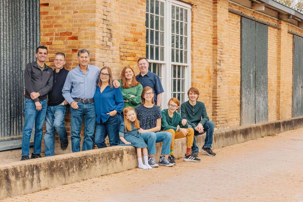 Family group seated on historic building steps in casual attire.