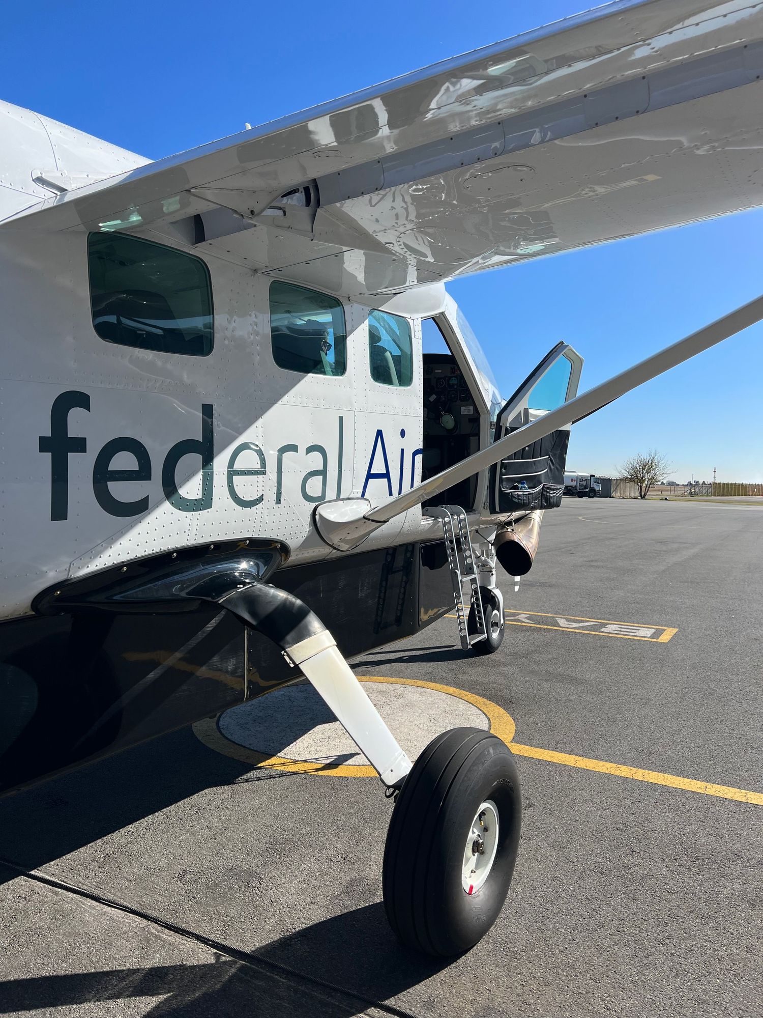 Small Federal Air aircraft parked on tarmac with white and green livery.