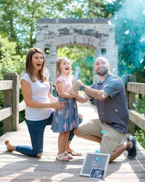 Family celebrates on wooden bridge with blue smoke effect and picture frame.
