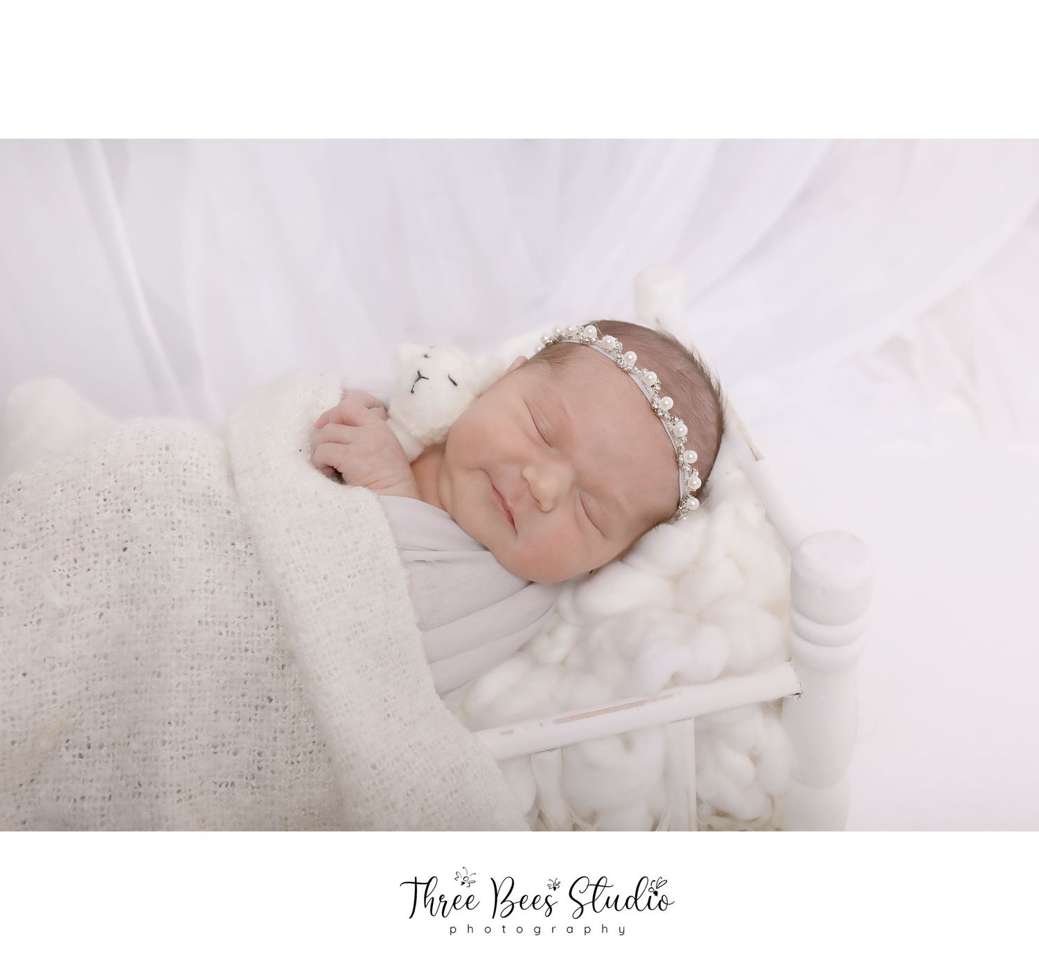 Newborn photography with white fabric and delicate floral headband.
