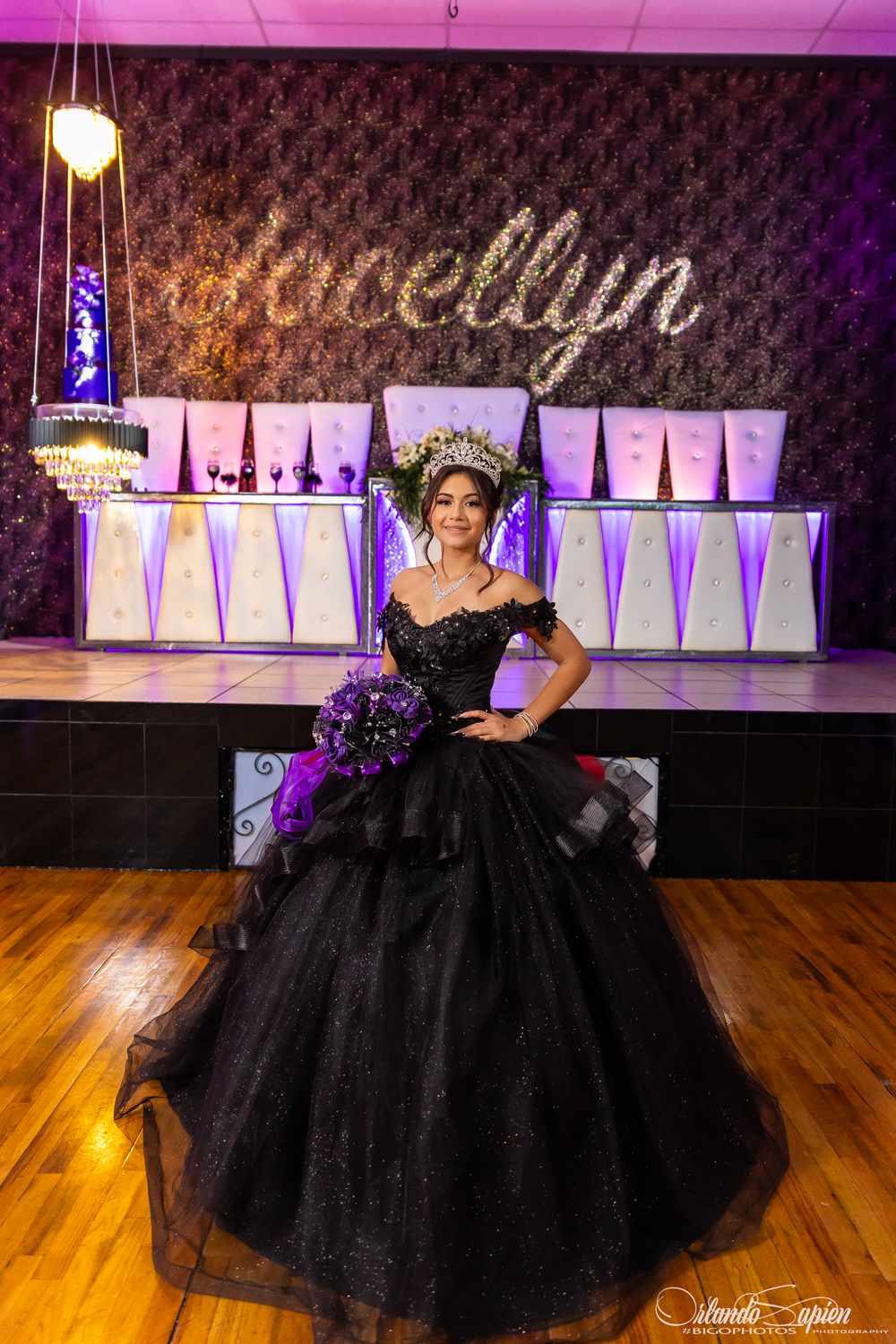 Elegant quinceanera celebration with illuminated signage and purple lighting in a ballroom setting.