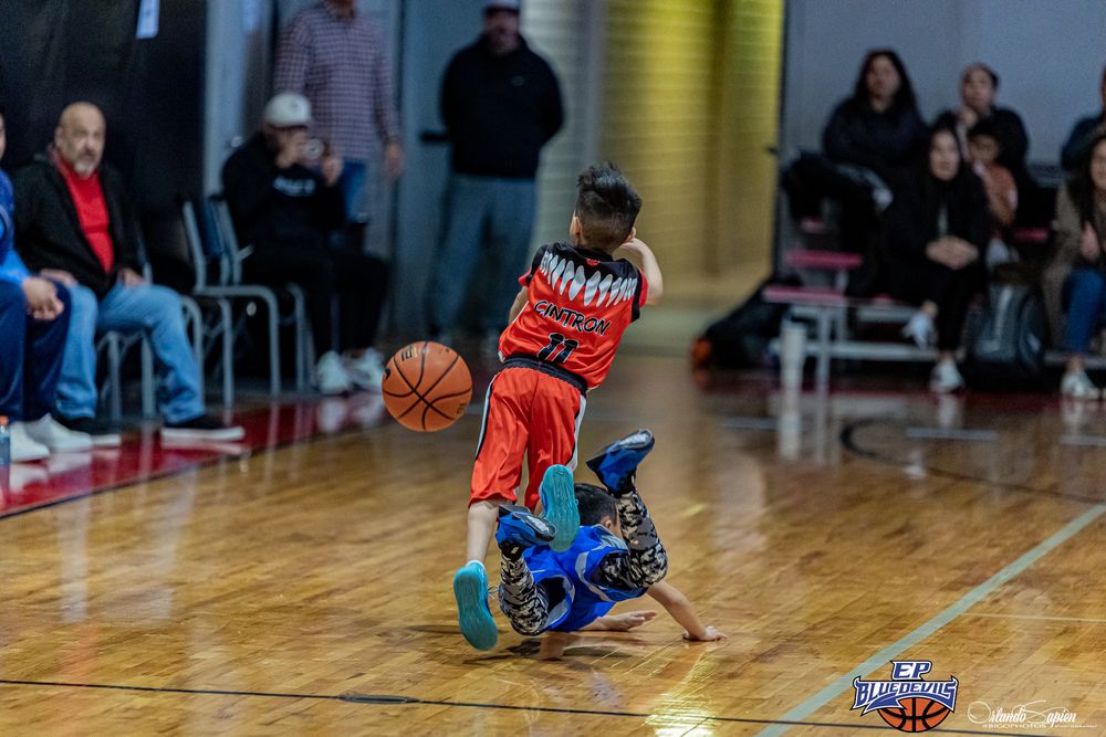 Basketball players in action on wooden court during game.