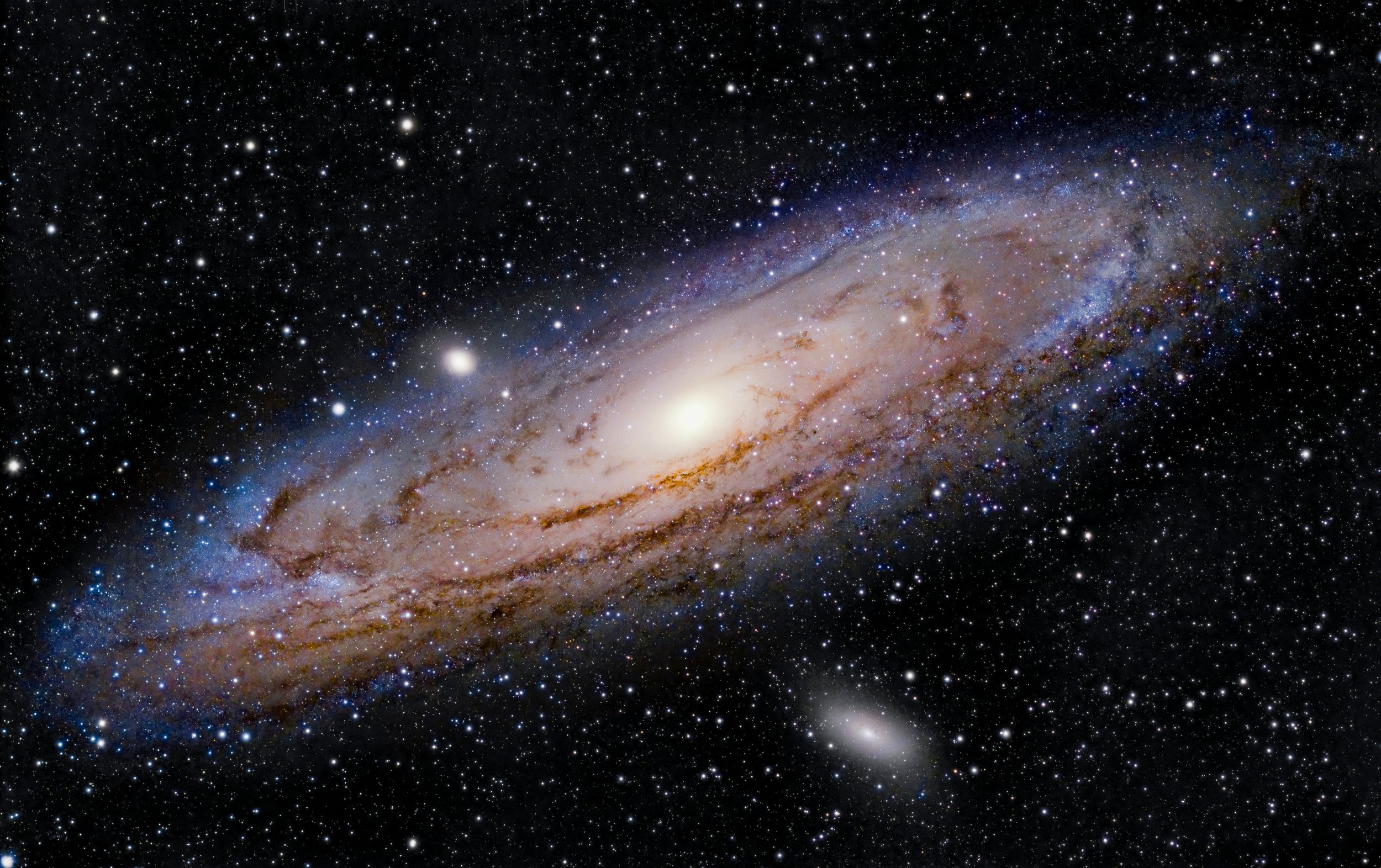 The Andromeda galaxy shines brilliantly against a dark starry background with its distinctive spiral arms.