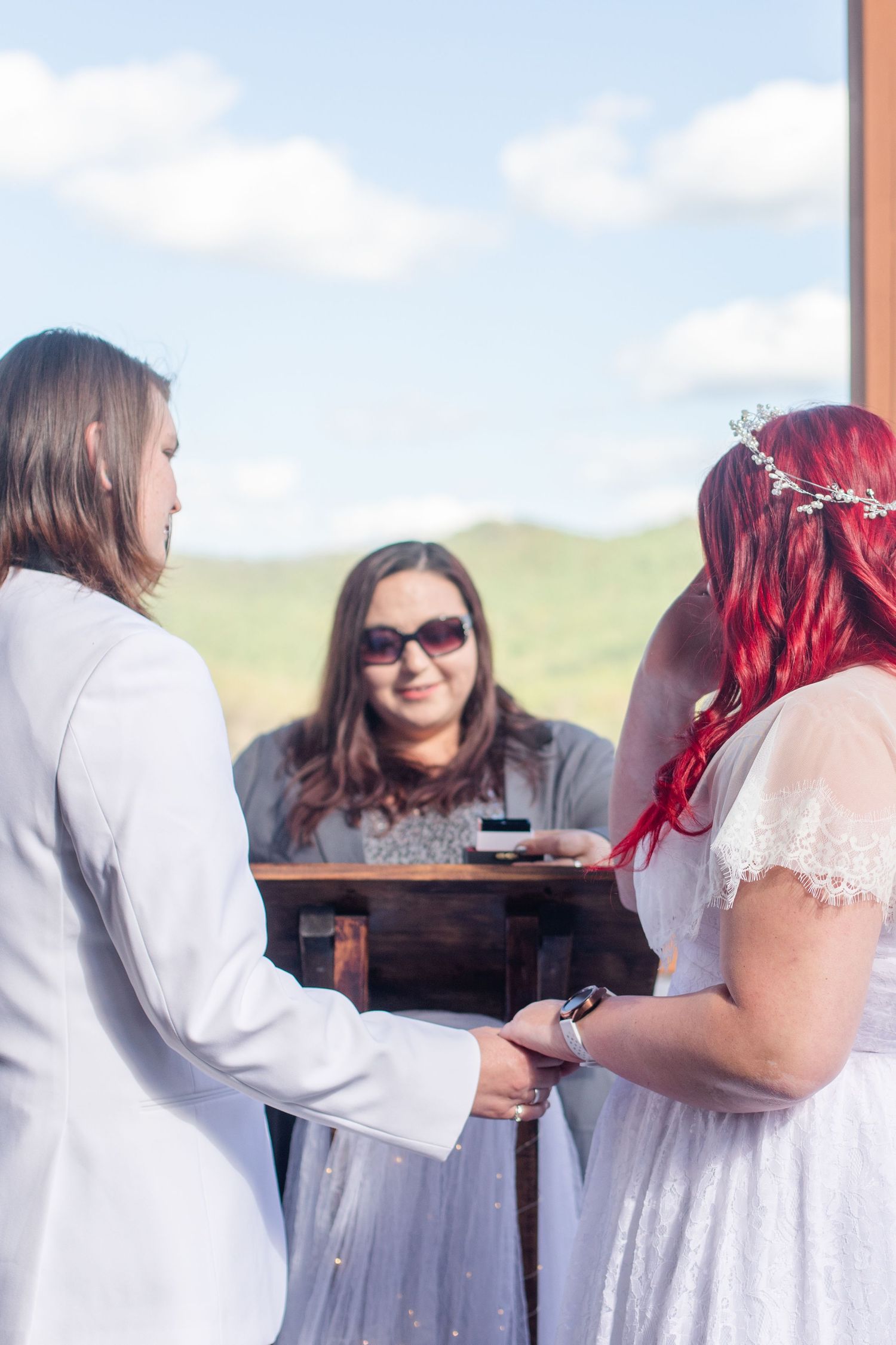 Wedding guests mingle on an outdoor deck with scenic mountain views in the background.