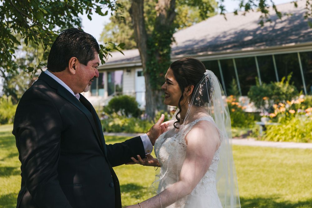 A couple exchanges rings during their outdoor wedding ceremony with a house in the background.