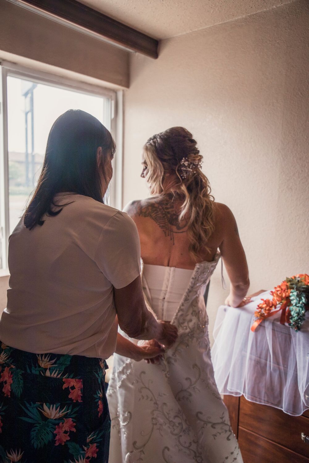 Wedding dress being laced up in front of window with natural light.