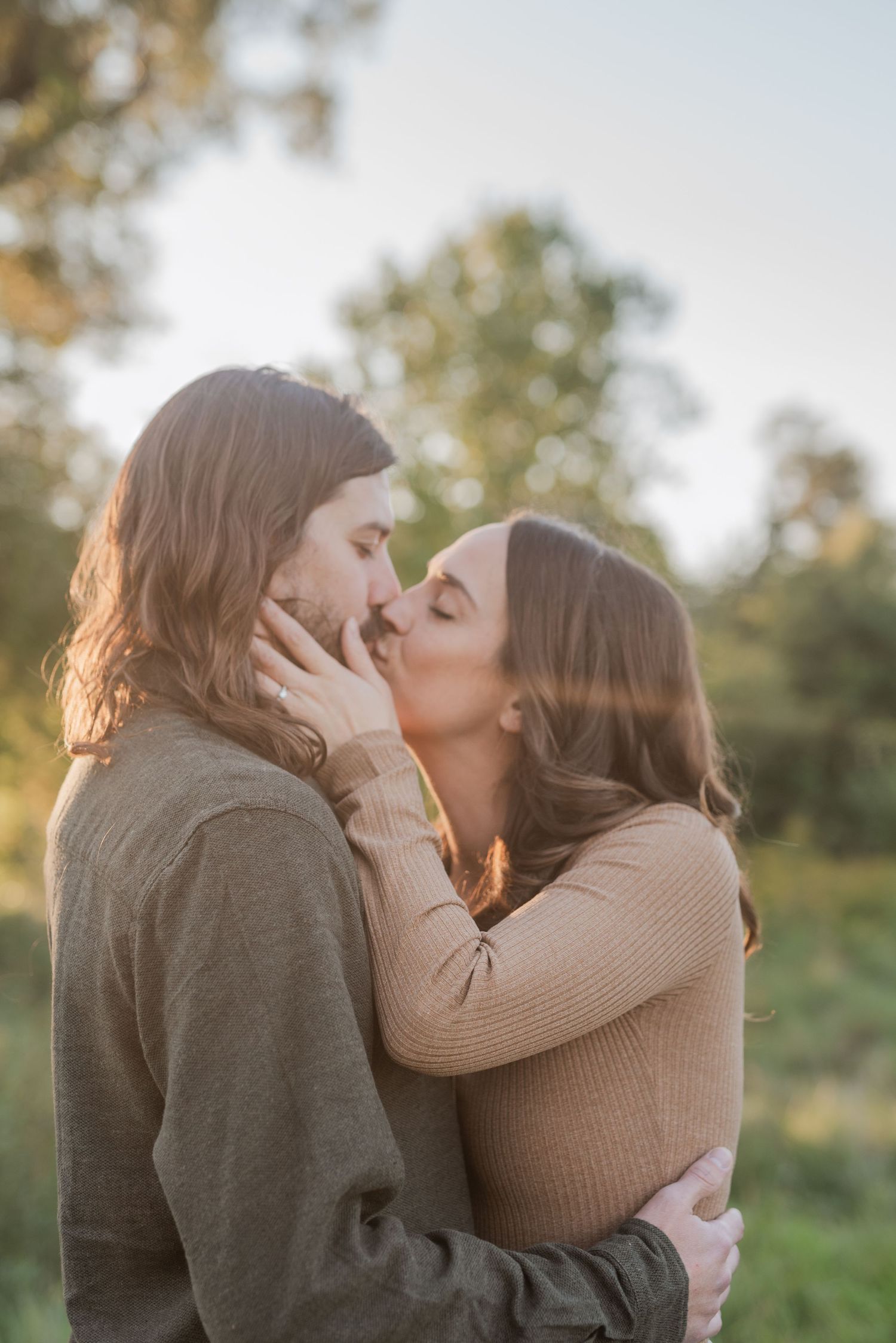 A tender moment captured between two people sharing a kiss in golden evening light.