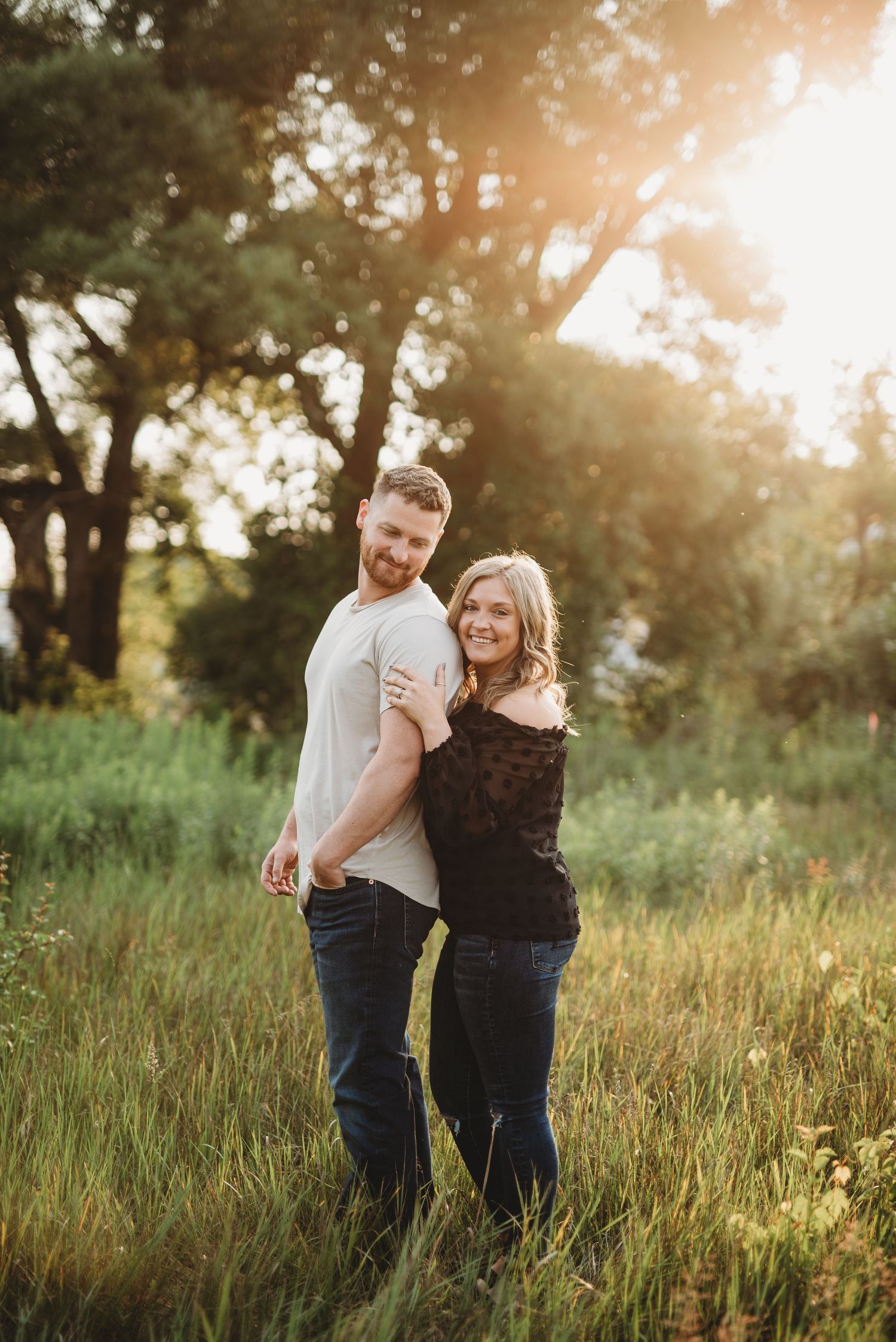 Golden hour portrait in a sunlit meadow with tall grass and trees.