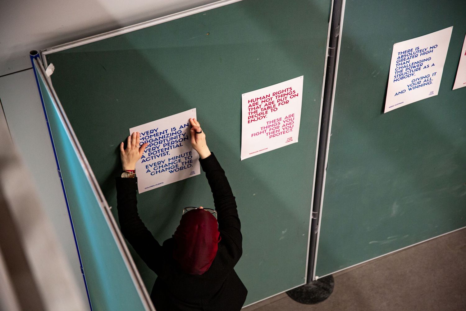 Person placing paper sign on green bulletin board at event.