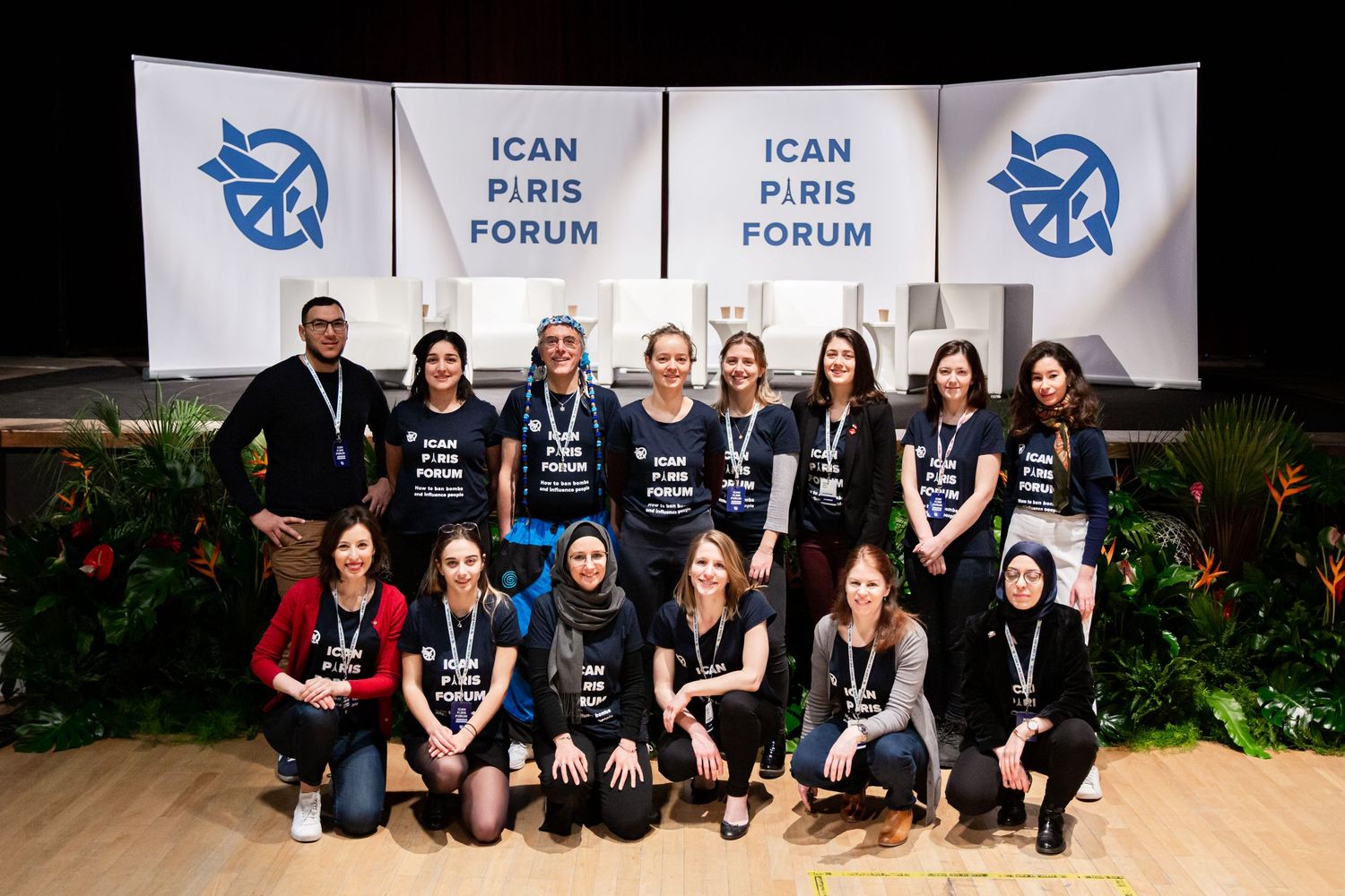 Group photo of ICAN Paris Forum participants posing in front of event banners.