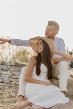 Couple in white outfits enjoying a tender moment on rocky terrain at golden hour.