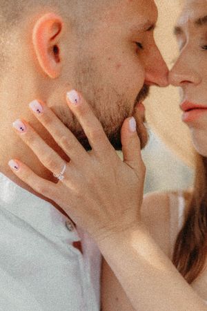 Close up of hands with manicured nails gently caressing during an intimate moment.