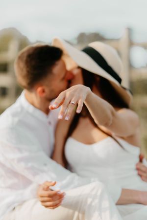 Romantic beach wedding scene showing a gentle embrace and sparkling engagement ring.