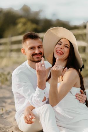 Sun-drenched beach portrait of a couple in white outfits sharing a joyful moment.