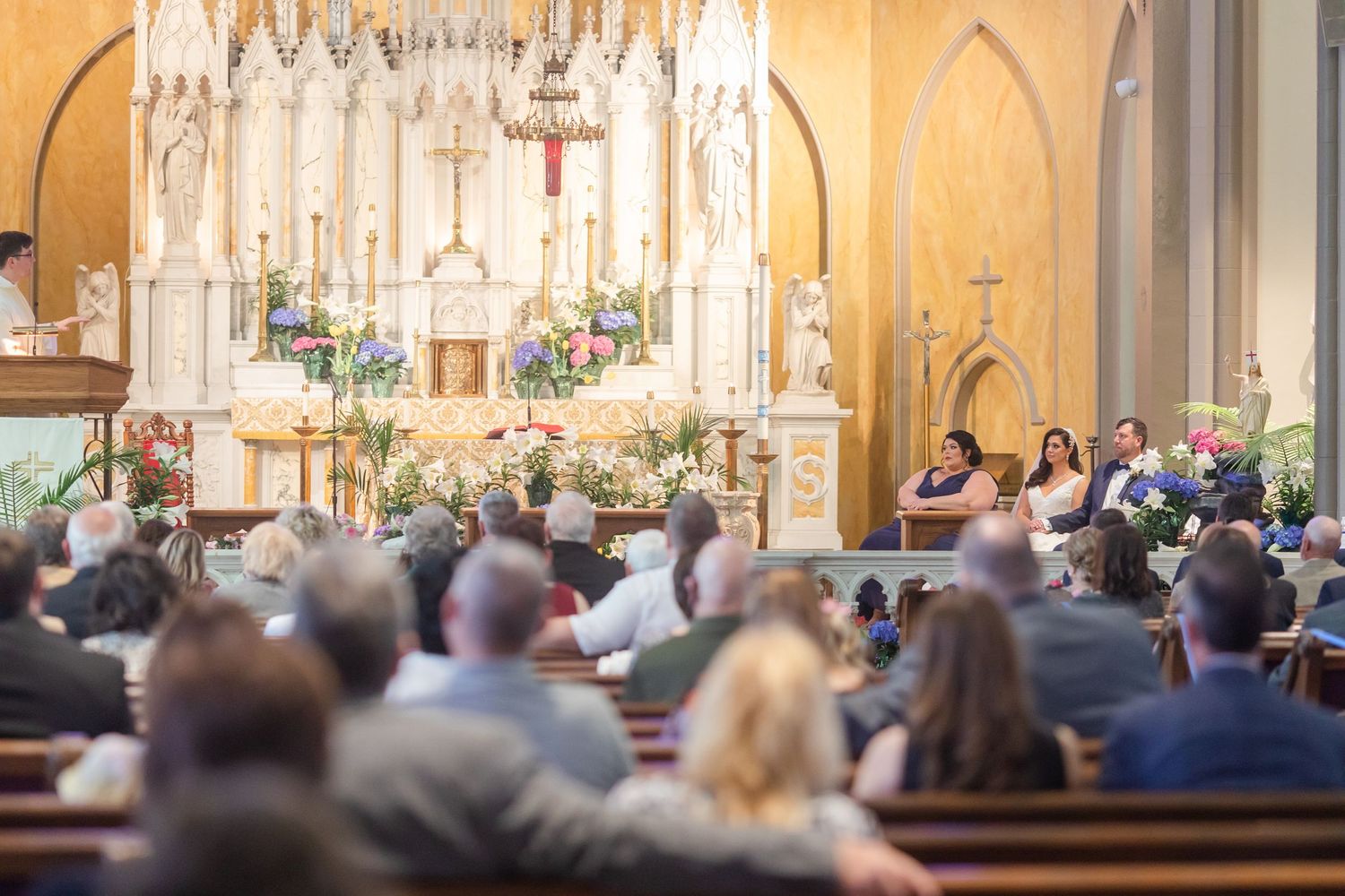 Panoramic view of Gothic church interior during wedding ceremony with filled pews.