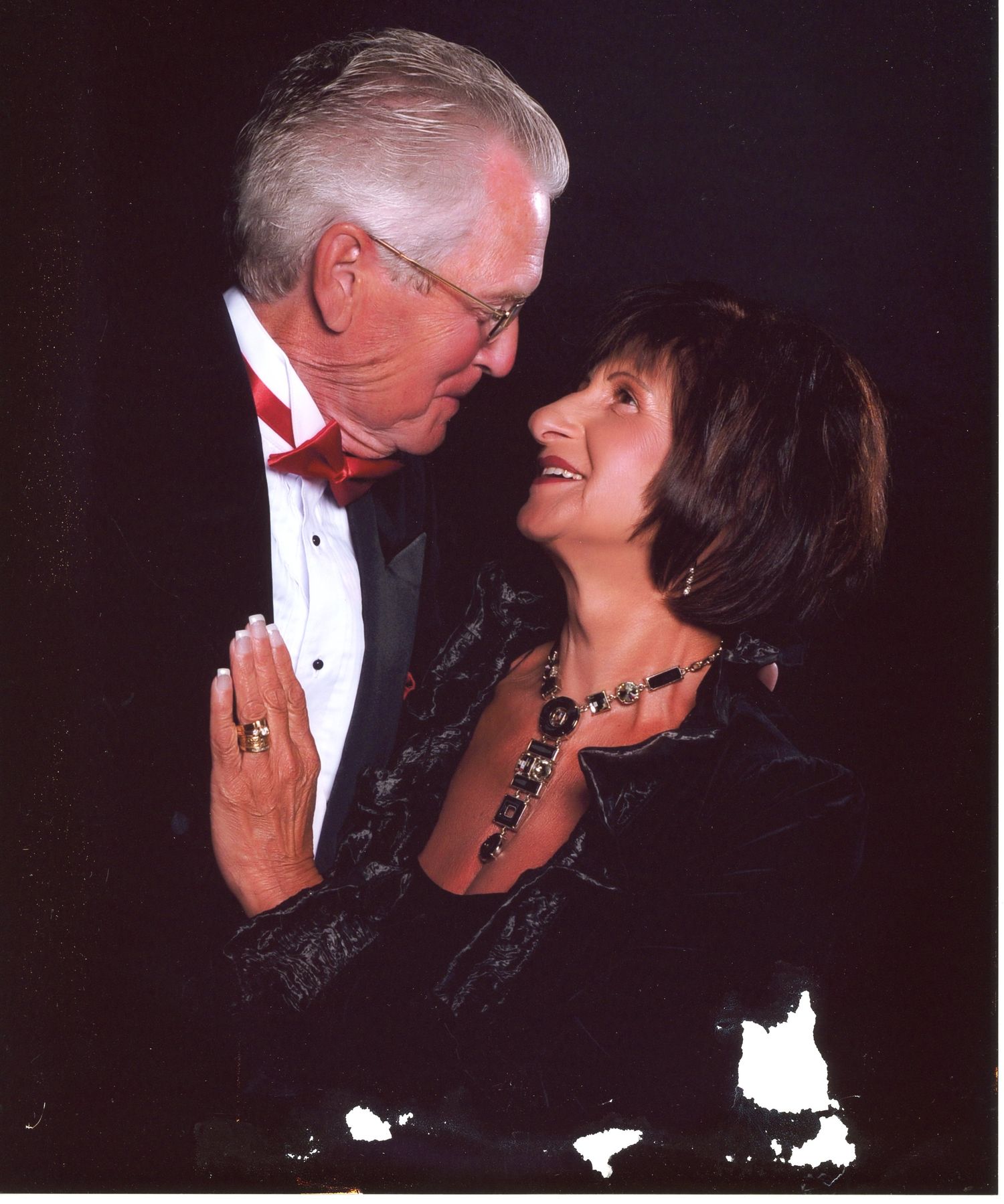 Couple in formal attire share intimate moment at black tie event.
