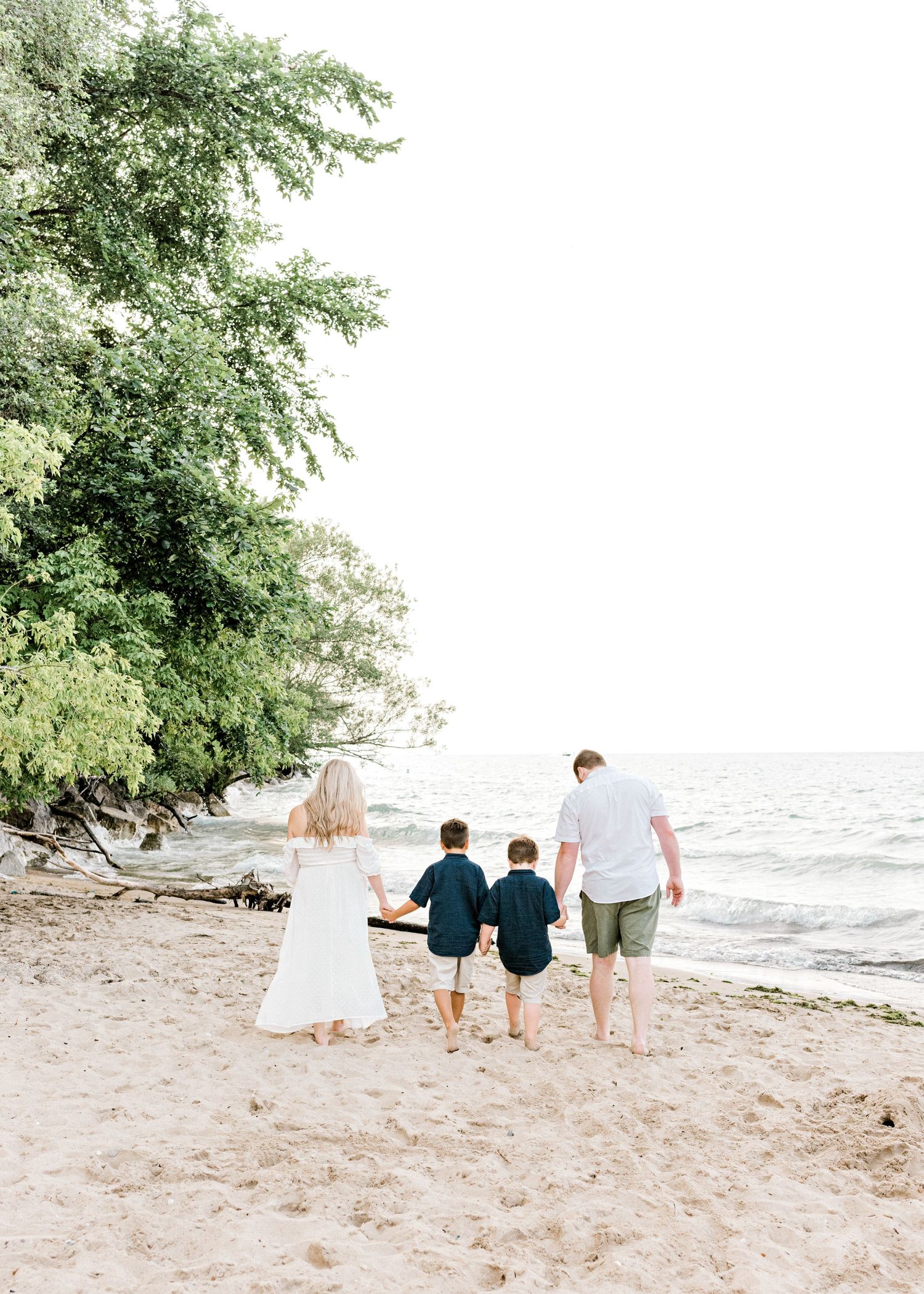 family of four walking hand and hand away from the camera on the beach