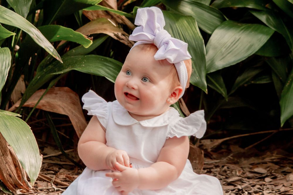 A baby girl sitting by plants in arsenal park in baton rouge