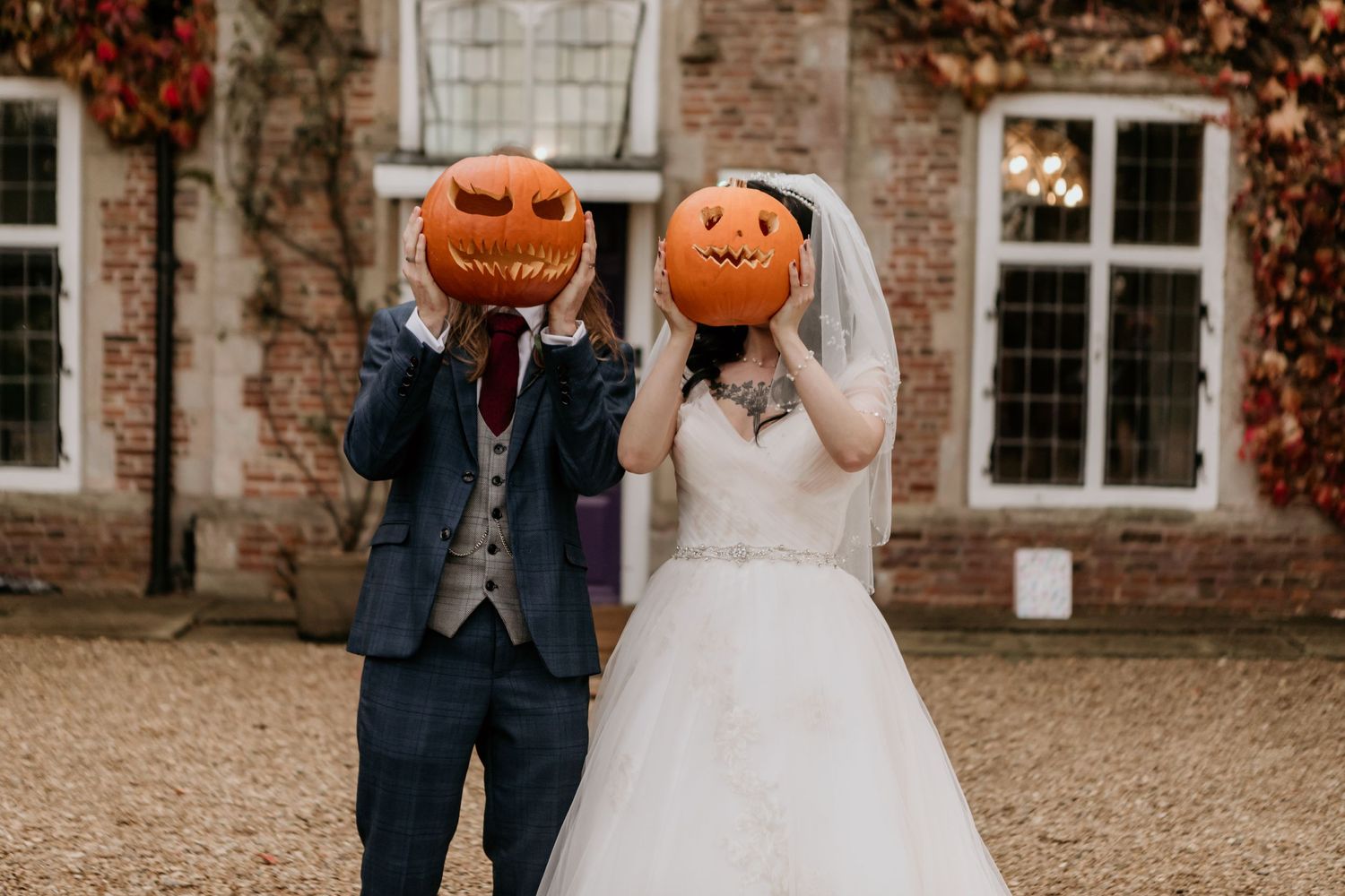 bride and groom holding pumpkins in front of faces