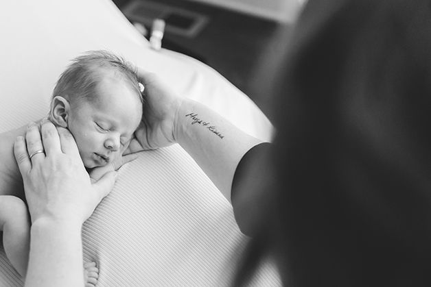 Black and white image of Laura, owner of Hope Believe Photography, posing a newborn baby boy.