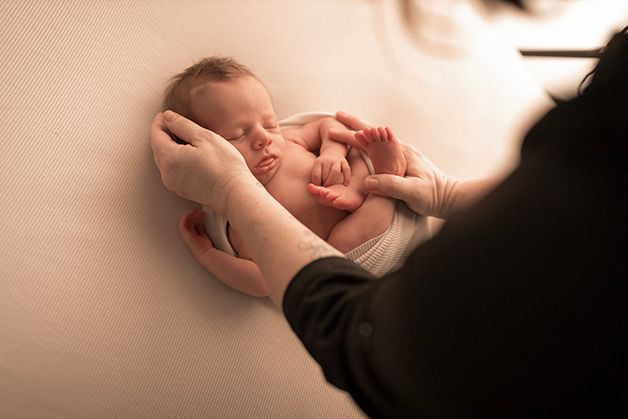 Laura from Hope Believe Photography posing a newborn baby boy in a womb like pose in her home studio in Evans, GA.
