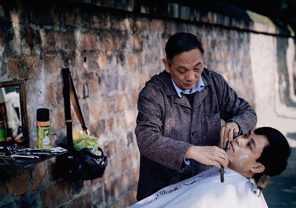 Street Barber in Hanoi by Adam West Photographer. Photographed on Kodak 160VC film.