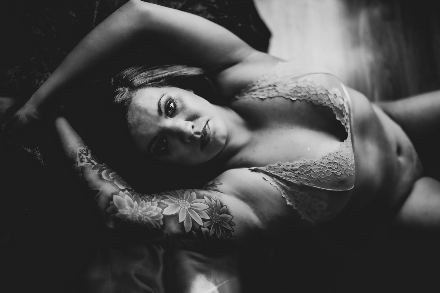 Black and white portrait showing woman in lace lingerie posing artistically.