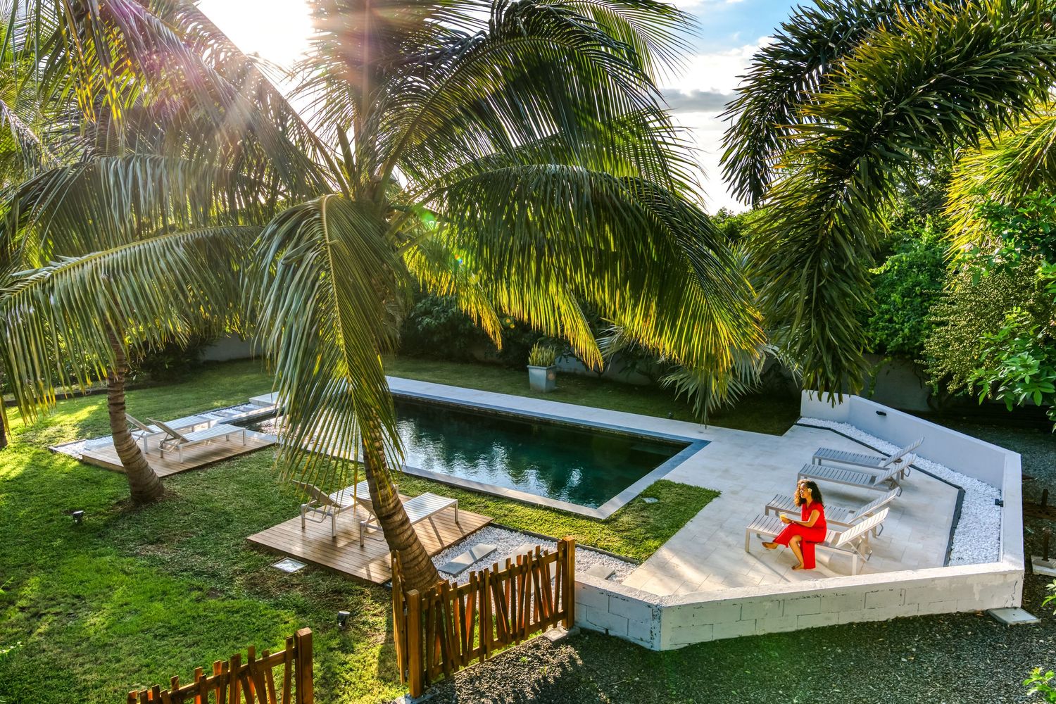 Aerial view of tropical swimming pool surrounded by lush palm trees and greenery.
