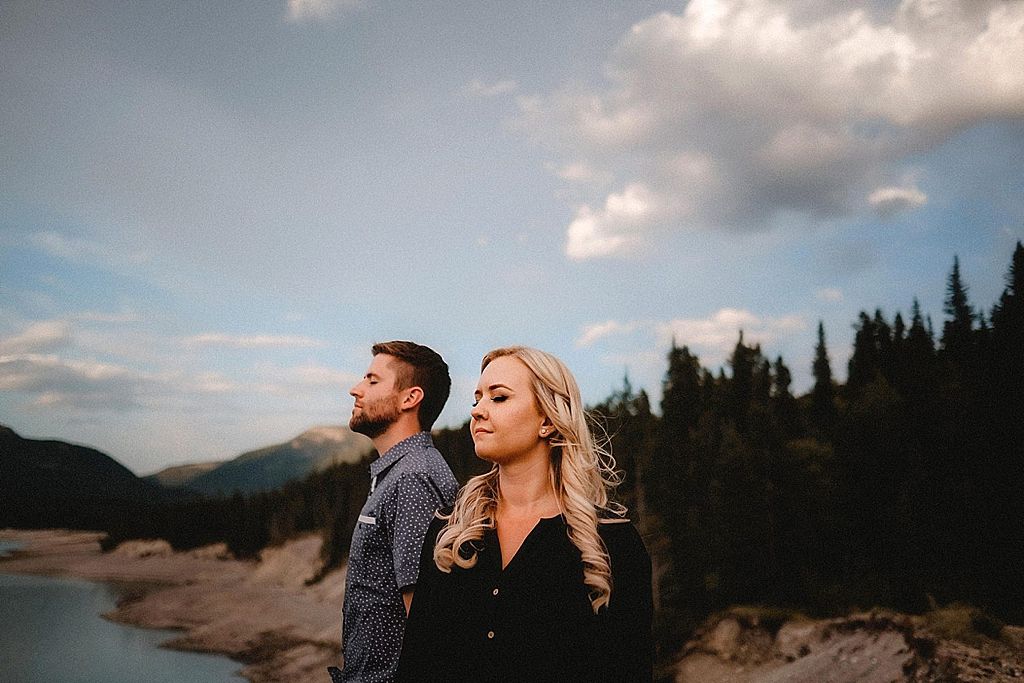 Couple enjoying scenic mountain lake view during sunset engagement session.