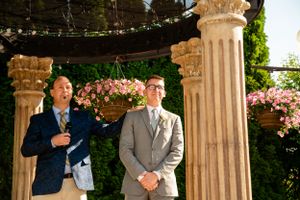 Evening wedding portraits under elegant stone gazebo with twinkling lights and flowers.