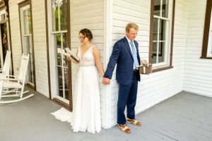 Wedding party posing on a white farmhouse porch with classic architectural details.