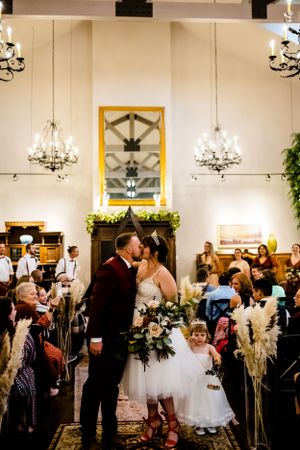 A romantic wedding ceremony moment in an elegant venue with chandeliers and decorative arches.