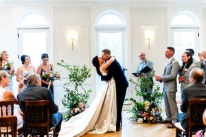 Indoor wedding ceremony in a bright, elegant white room with natural light.