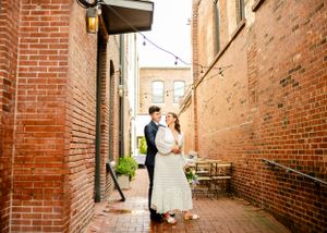 Wedding couple shares intimate moments in a rustic brick alleyway setting.