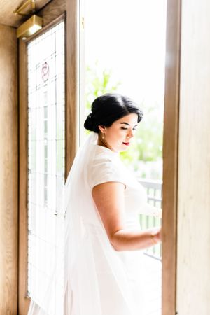 Elegant bridal preparation moment by sunlit window.