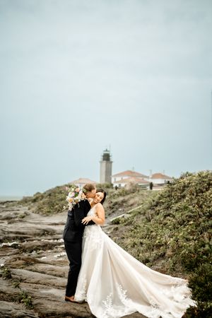 Dramatic coastal wedding photos with a lighthouse in the background.