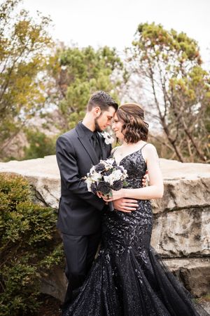 A romantic moment captured against a stone wall backdrop with formal attire.