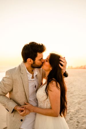 Romantic sunset beach portraits with couple in wedding attire.