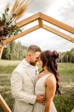Romantic moment captured under wooden pergola in outdoor setting.