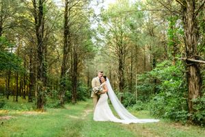 Romantic forest wedding photo session with trees creating natural archways.
