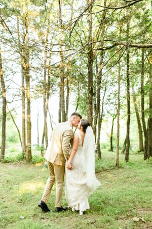 Wedding couple shares romantic moments in a sunlit wooded area.