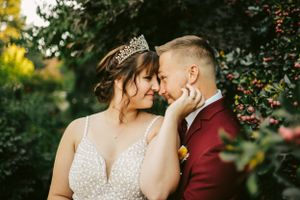 Romantic wedding portrait captured in natural garden setting with soft lighting.